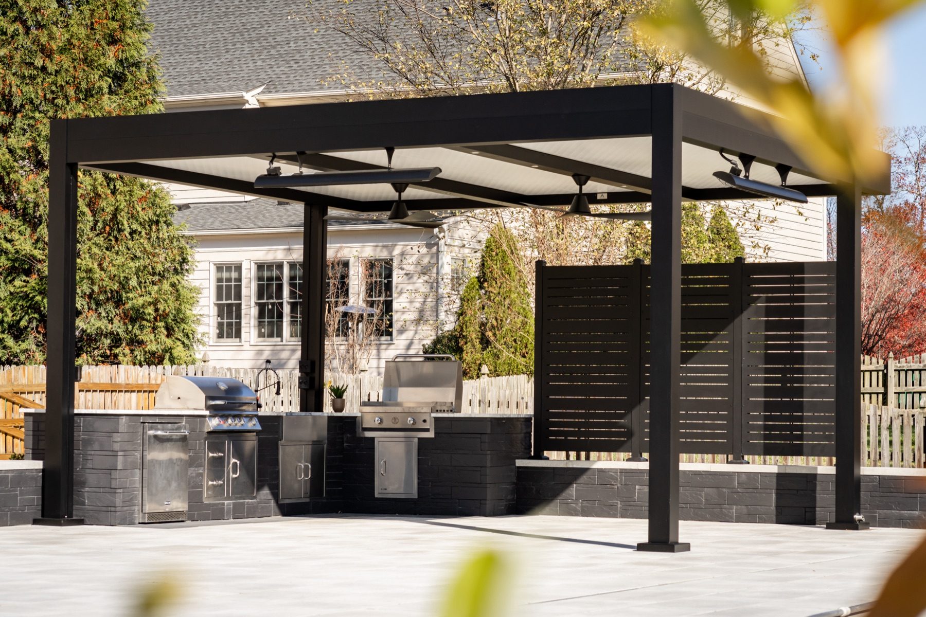 Motorized louvered pergola installed over a residential outdoor dining and lounge area