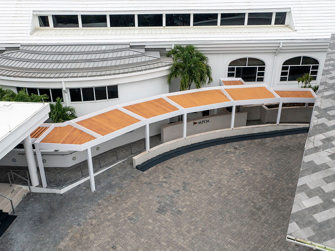 Pergolas alignées formant un passage couvert en bois devant bâtiment blanc