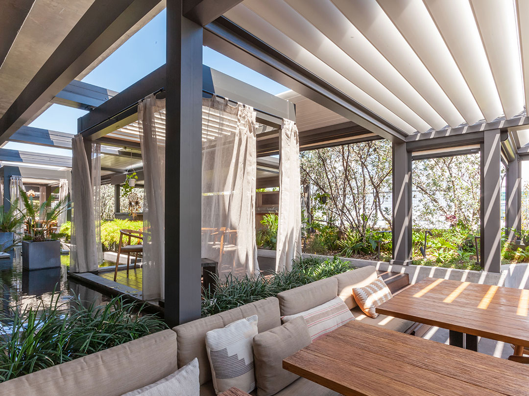Terrasse de restaurant en bois sous pergola bioclimatique avec lames orientables