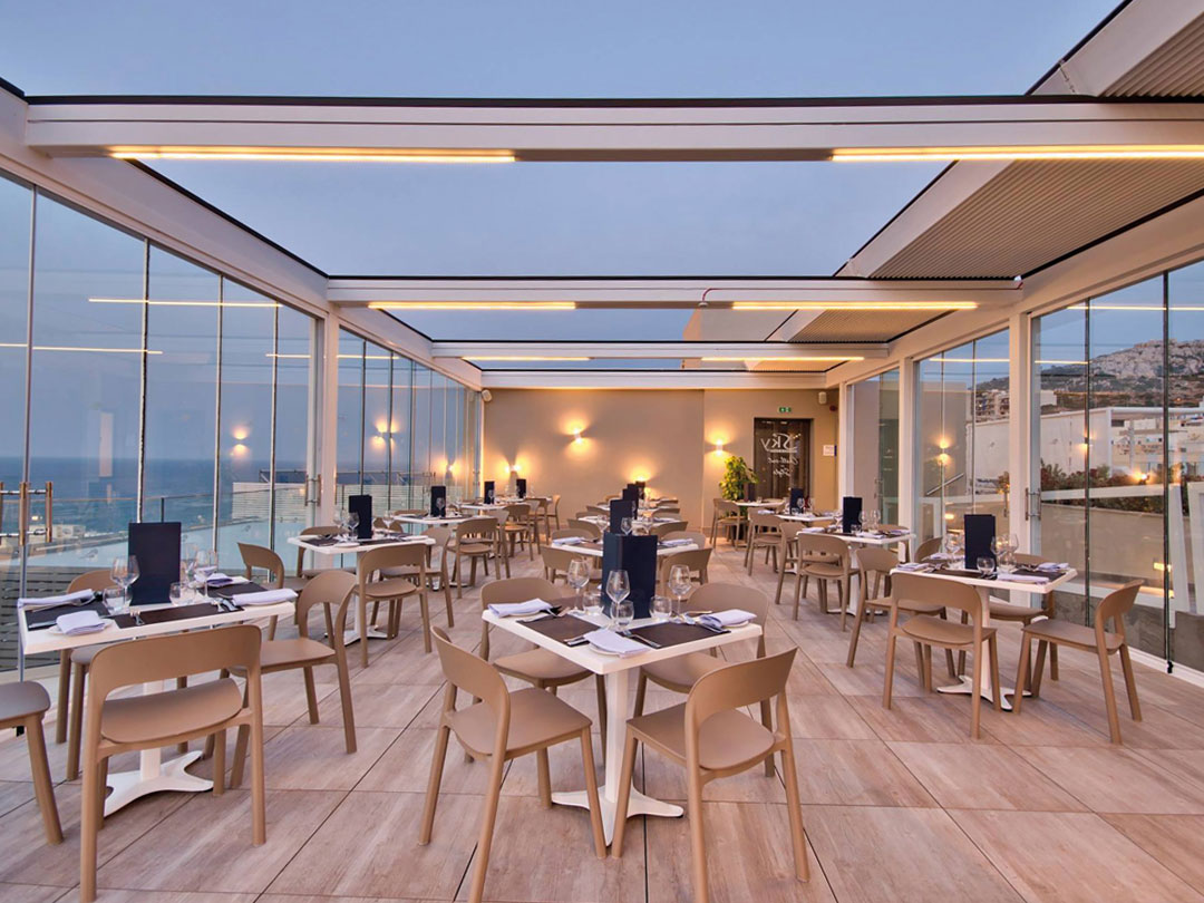 Terrasse panoramique en bord de mer abritée par une pergola à lames orientables et rétractables